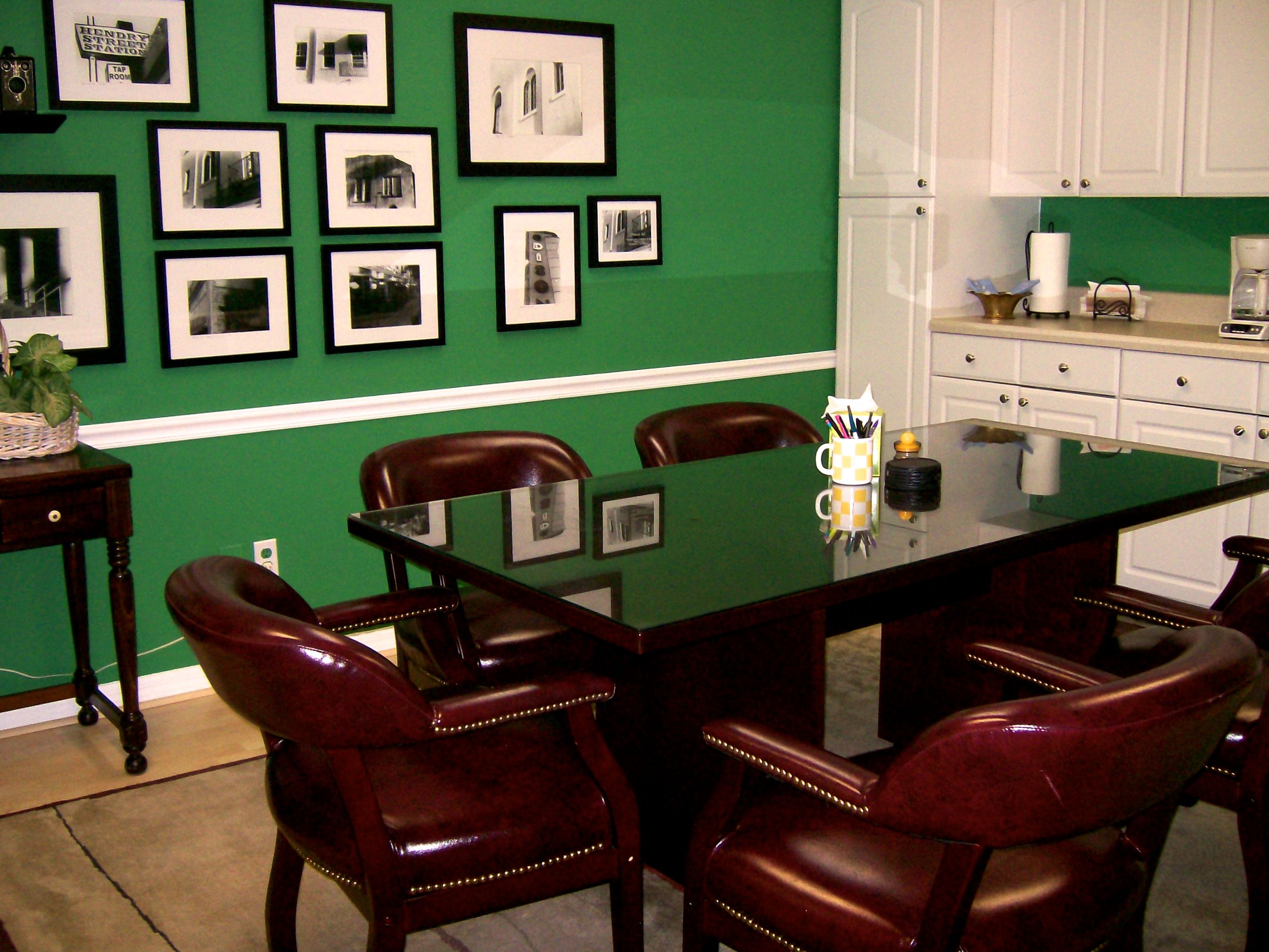 Conference room with table and chairs, kitchenette and pictures on the wall